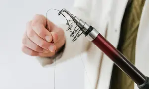 Dłoń trzymająca żyłkę przy końcu wędki z przelotkami.