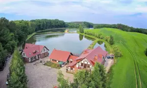 Malownicza osada rybacka Sazan z czerwonymi dachami, otoczona stawami i zielonymi polami.