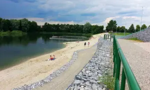 Żwirownia międzyrzec podlaski: piaszczysta plaża, kąpielisko z pomostami, ludzie odpoczywający nad wodą, zielone drzewa w tle.