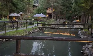 Malownicza okolica bobcikowa chata Szczawnica z drewnianymi mostkami nad strumieniem i oświetlonymi altanami.