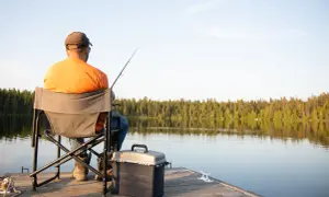 Wędkarz na pomoście, zastanawia się, ile kosztuje wyrobienie karty rybackiej.
