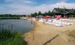 Słoneczny dzień na plaży, gdzie łowisko wilga wodna kraina zaprasza do kąpieli i relaksu. Leżaki i parasole czekają na plażowiczów.