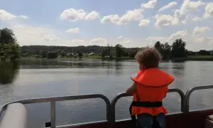 Dziecko w kamizelce ratunkowej podziwia widok na rzekę i lasy. Idealne miejsce na wypoczynek w agroturystyce "Bagna u Mańka".