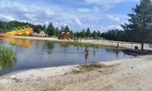Sielska woda zaprasza do zabawy! Dzieci kąpią się, a w tle dmuchane zjeżdżalnie i plac zabaw. Sprawdź cennik i przyjedź!