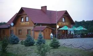 Drewniany budynek z napisem "Zajazd u Bartka" i zielonymi parasolami przed wejściem.