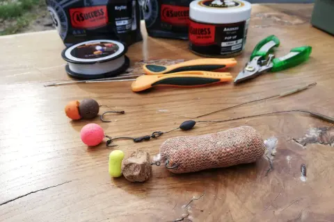 Zestaw karpiowy do rzutu z pva: kulki proteinowe, haczyki, żyłka, nożyczki i siatka PVA z zanętą.