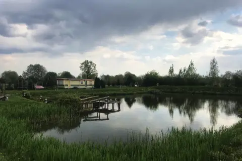Łowisko Cicha Woda Niedrzwica Duża: spokojna tafla wody, przytulny domek i drewniany pomost.
