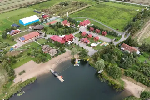 Malownicza jeziorna osada Gnojewo z piaszczystą plażą, pomostami i licznymi budynkami wypoczynkowymi.