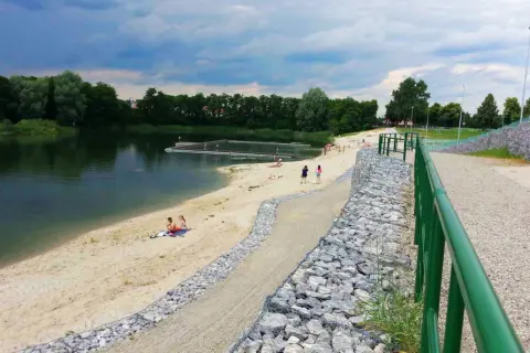 Żwirownia międzyrzec podlaski: piaszczysta plaża, kąpielisko z pomostami, ludzie odpoczywający nad wodą, zielone drzewa w tle.