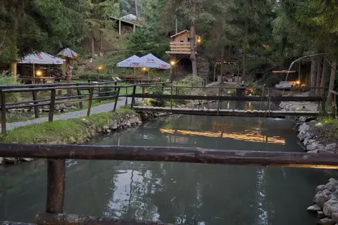 Malownicza okolica bobcikowa chata Szczawnica z drewnianymi mostkami nad strumieniem i oświetlonymi altanami.