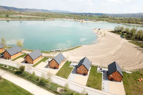 Drewniane domki nad turkusową wodą, idealne na wypoczynek w stylu kąpielisko Mała Chorwacja. Piękny piasek i zieleń wokół.