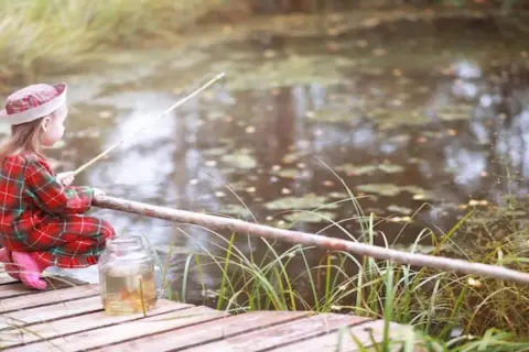 Mała wędkarza z Wielkopolski, z wędką i słoikiem na ryby, szuka idealnego miejsca gdzie na ryby z noclegiem.