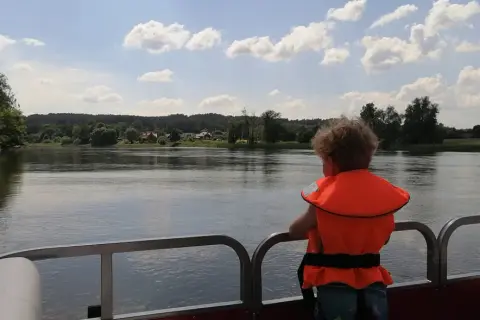 Dziecko w kamizelce ratunkowej podziwia widok na rzekę i lasy. Idealne miejsce na wypoczynek w agroturystyce "Bagna u Mańka".