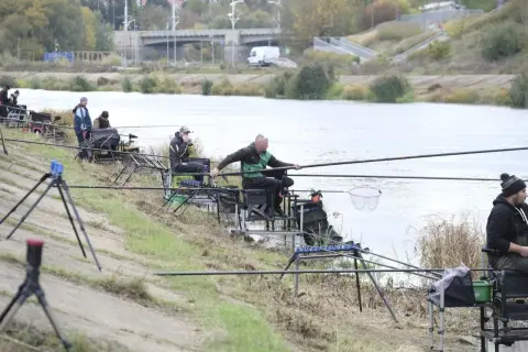 Wędkarze nad rzeką, zastanawiają się, ile kosztuje karta wędkarska w Polsce, by móc legalnie łowić ryby.
