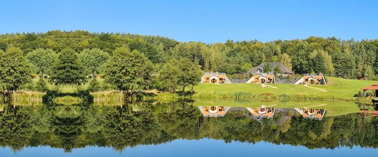 Urocze domki w stylu hobbitów nad jeziorem, tworzące bajkowy wodny świat Ostrzyce.