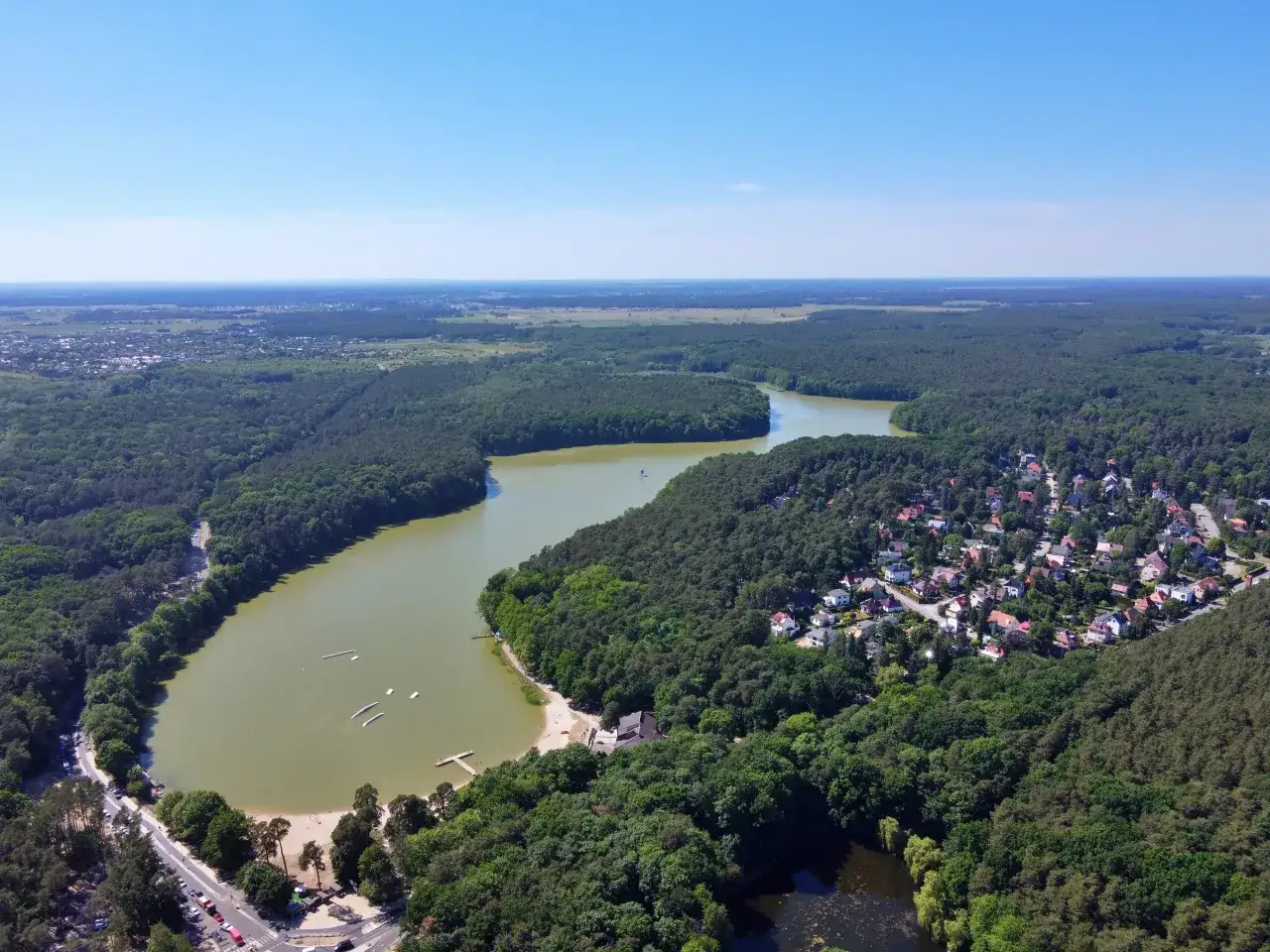 Malownicze jezioro Głębokie w województwie lubelskim otoczone lasem, z widocznymi domami i plażą.