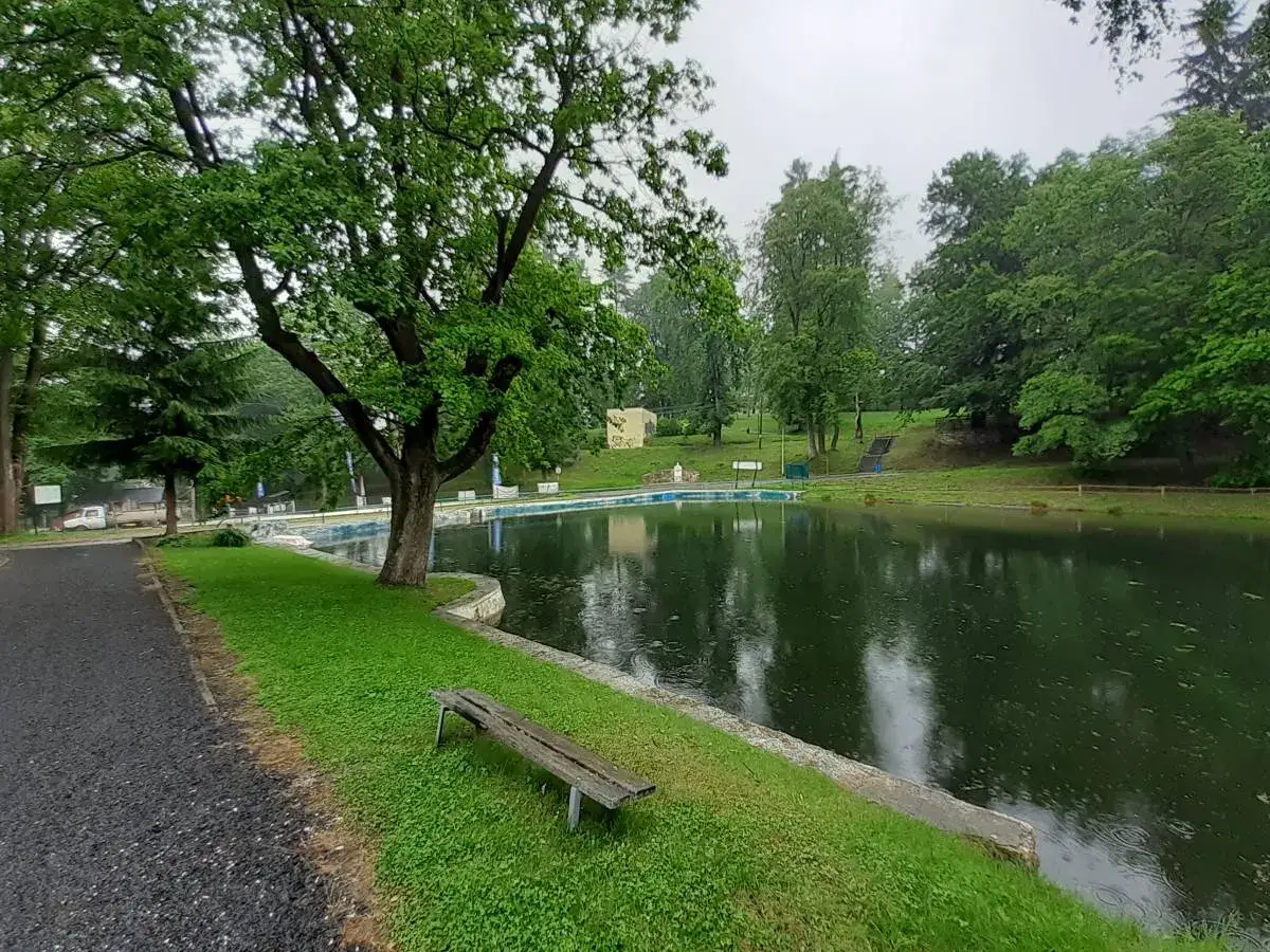 Spokojne stawy Biskupie w Lądku-Zdroju, otoczone zielenią, z ławką i ścieżką.