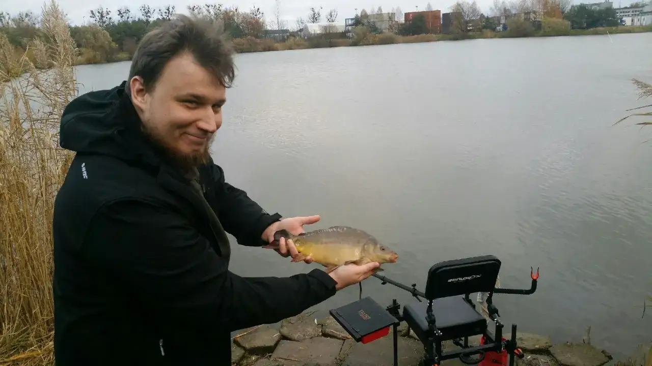 Szczęśliwy wędkarz z karpiem na łowisku Jaguar Gdańsk.