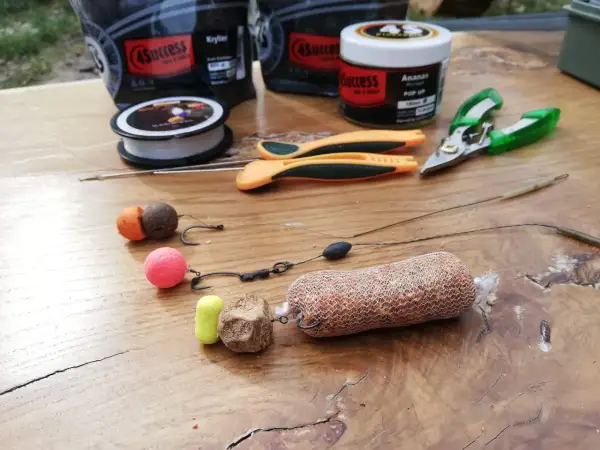 Zestaw karpiowy do rzutu z pva: kulki proteinowe, haczyki, żyłka, nożyczki i siatka PVA z zanętą.