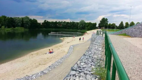 Żwirownia międzyrzec podlaski: piaszczysta plaża, kąpielisko z pomostami, ludzie odpoczywający nad wodą, zielone drzewa w tle.